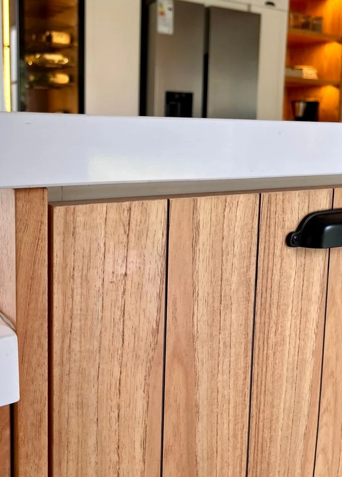 Frente de listones de madera clara bajo una mesada blanca