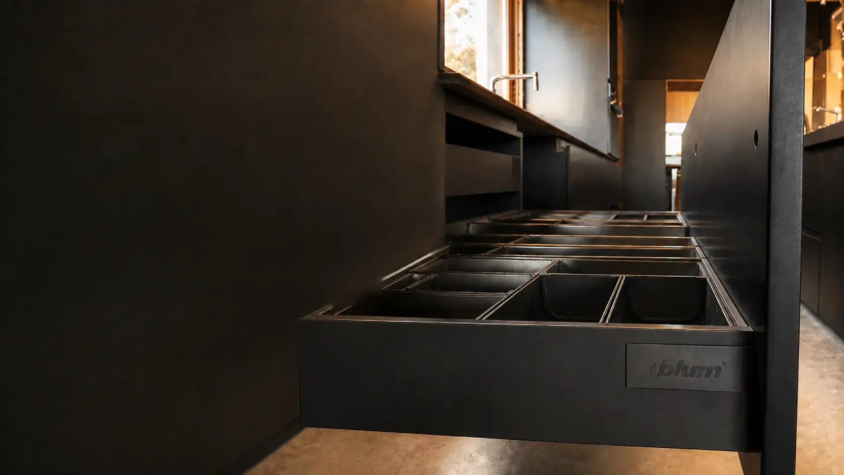 Cajón negro con organización interior y herrajes Blum en una cocina de Formas